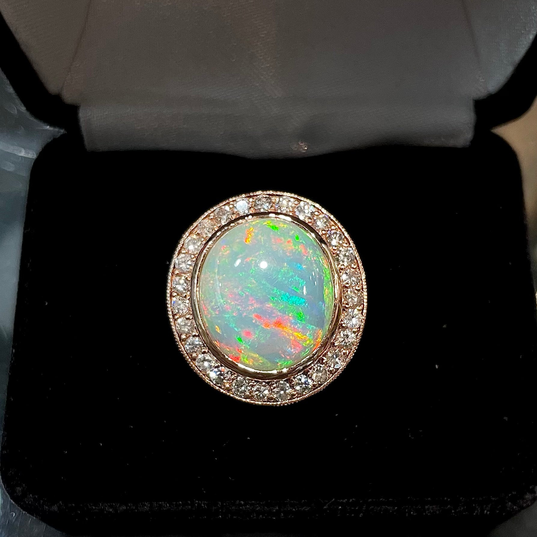 A large, Australian white crystal opal set in a rose gold and diamond halo ring.