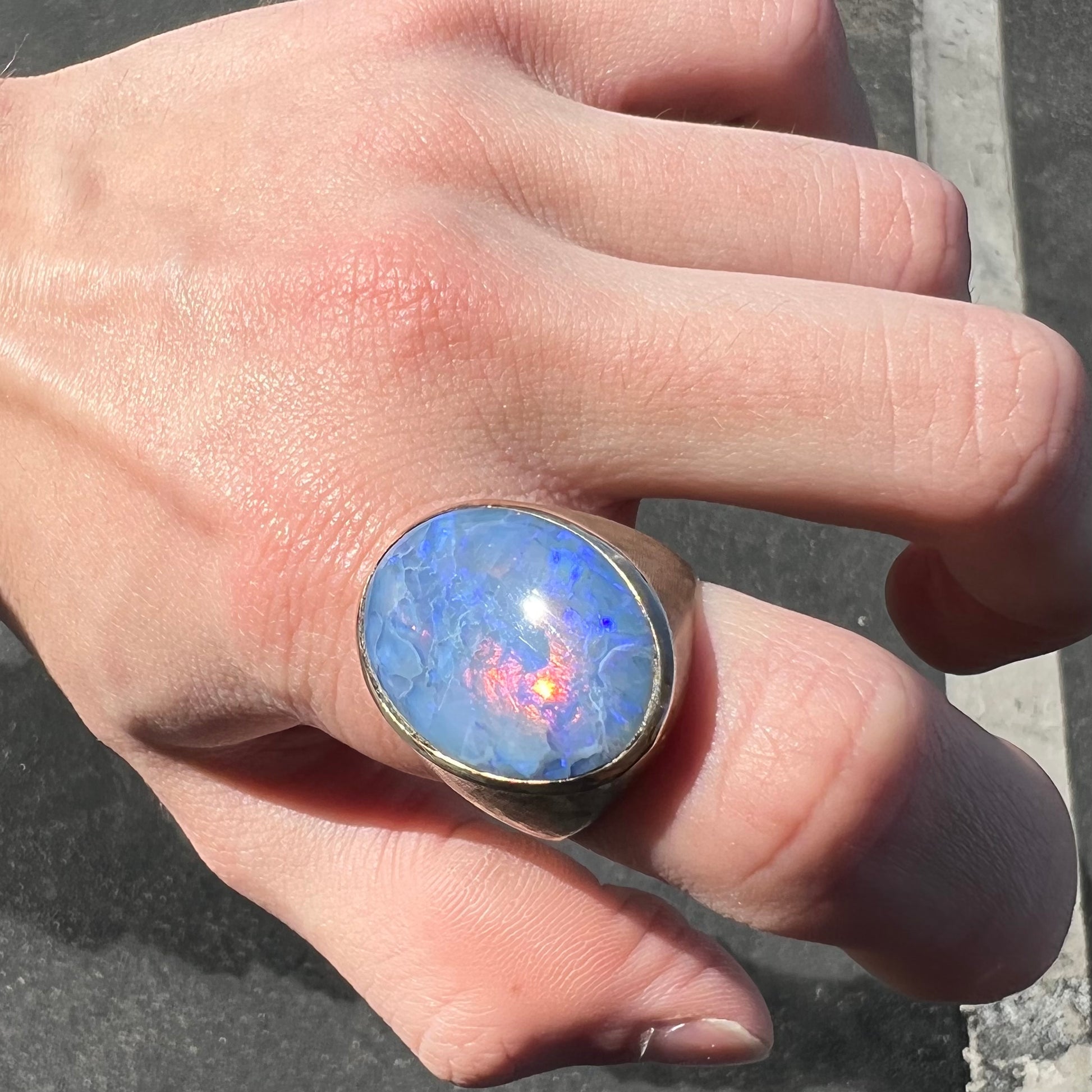 A Lightning Ridge black opal men's ring in solid yellow textured gold.