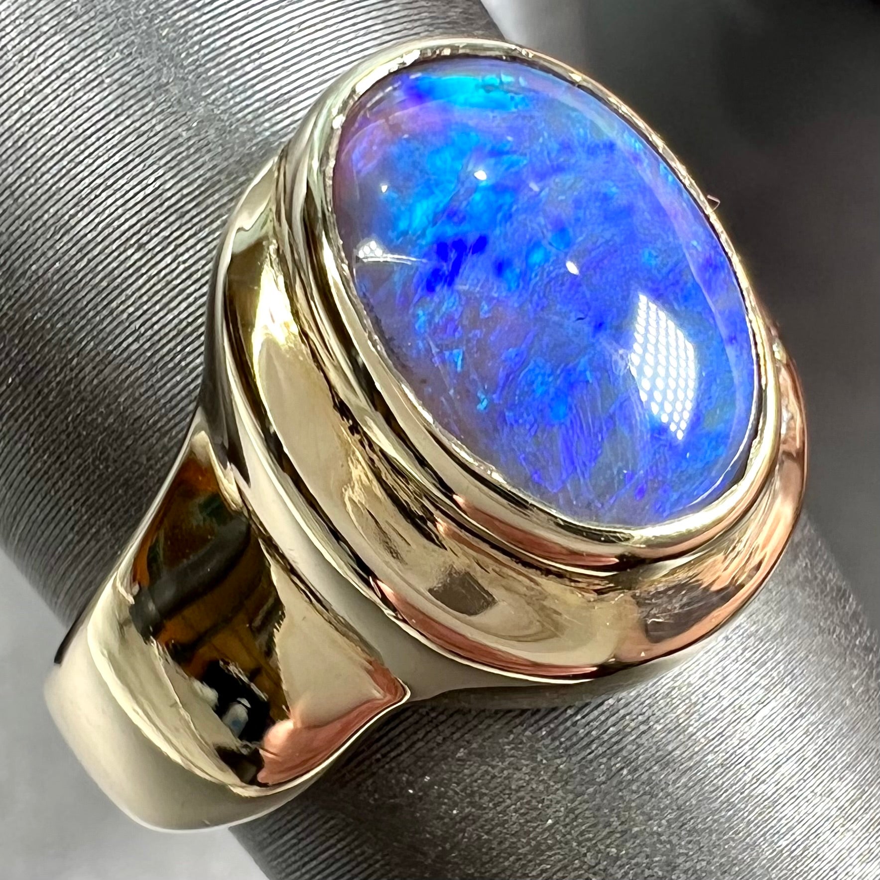 A yellow gold ring set with diamonds and a Lightning Ridge black opal from Australia.