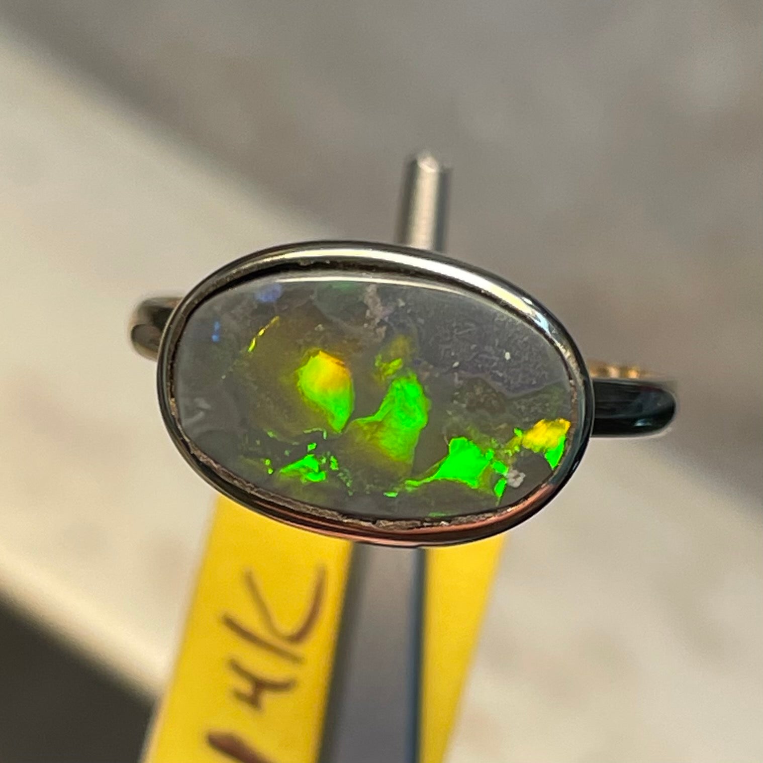 A handmade Lightning Ridge black opal solitaire ring in yellow gold.  Fire is green.