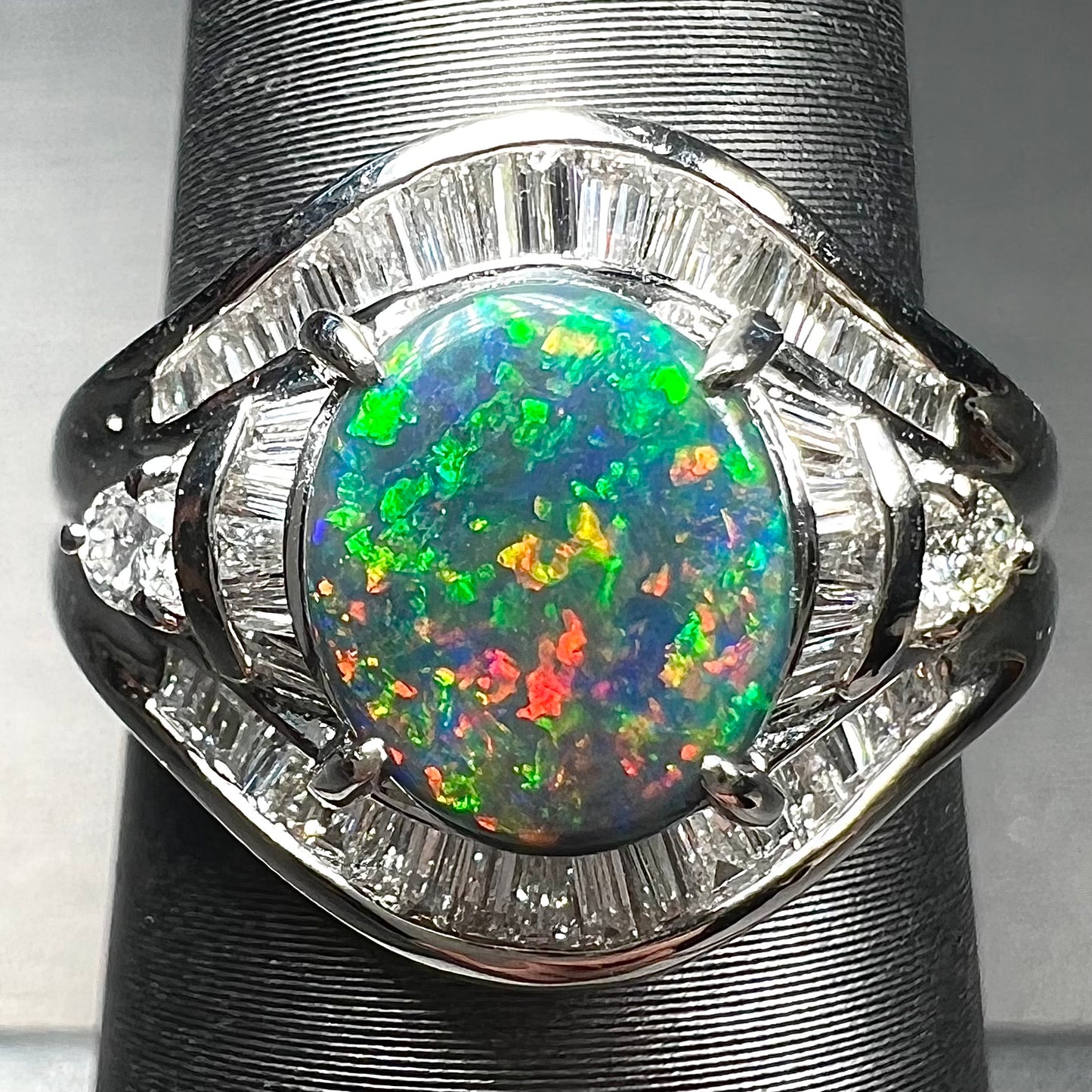 A platinum Lightning Ridge black opal ring set with baguette cut diamonds.  The opal is an oval cabochon cut.