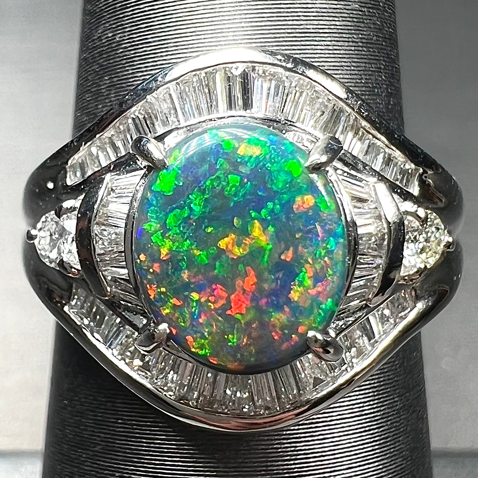 A platinum Lightning Ridge black opal ring set with baguette cut diamonds.  The opal is an oval cabochon cut.