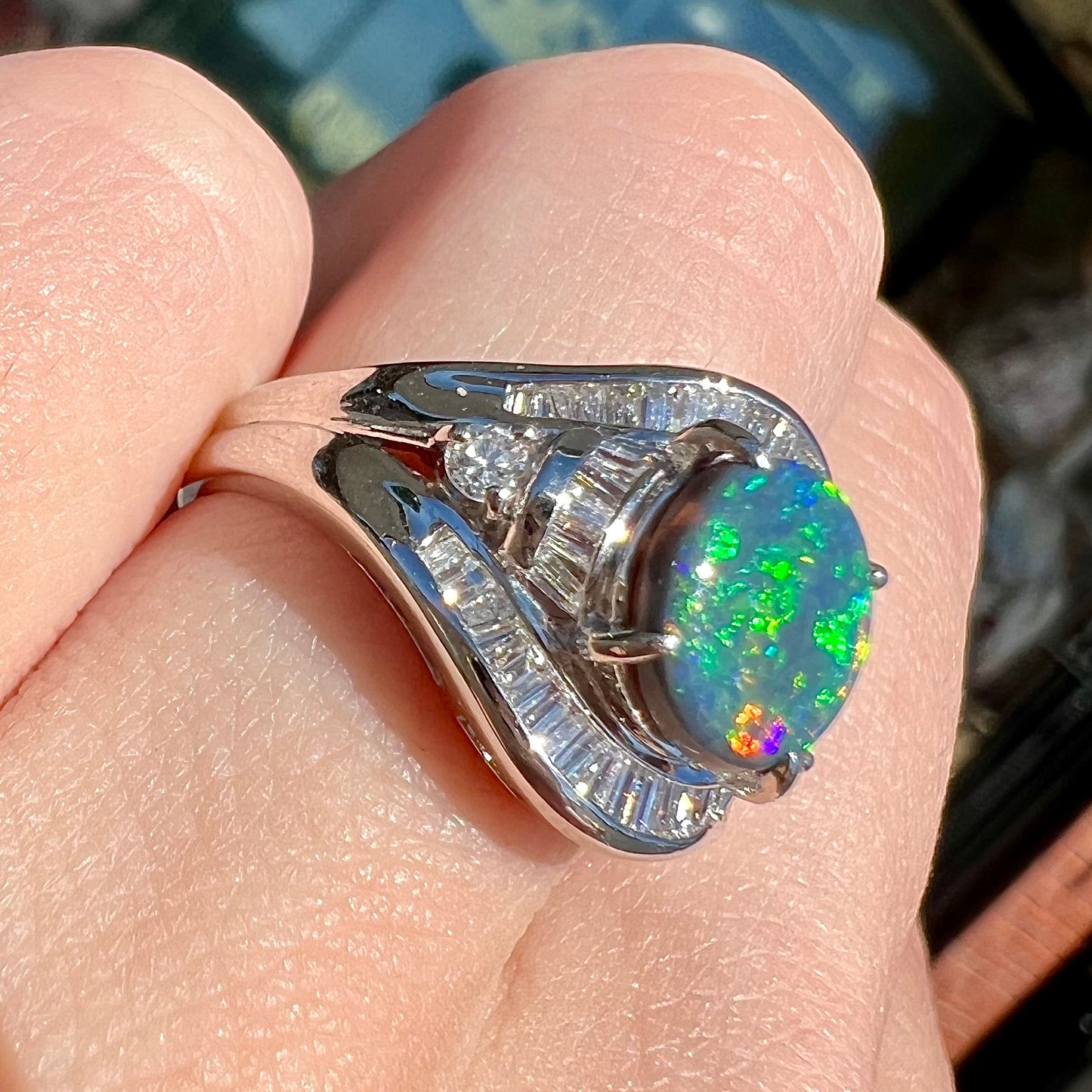 A platinum Lightning Ridge black opal ring set with baguette cut diamonds.  The opal is an oval cabochon cut.