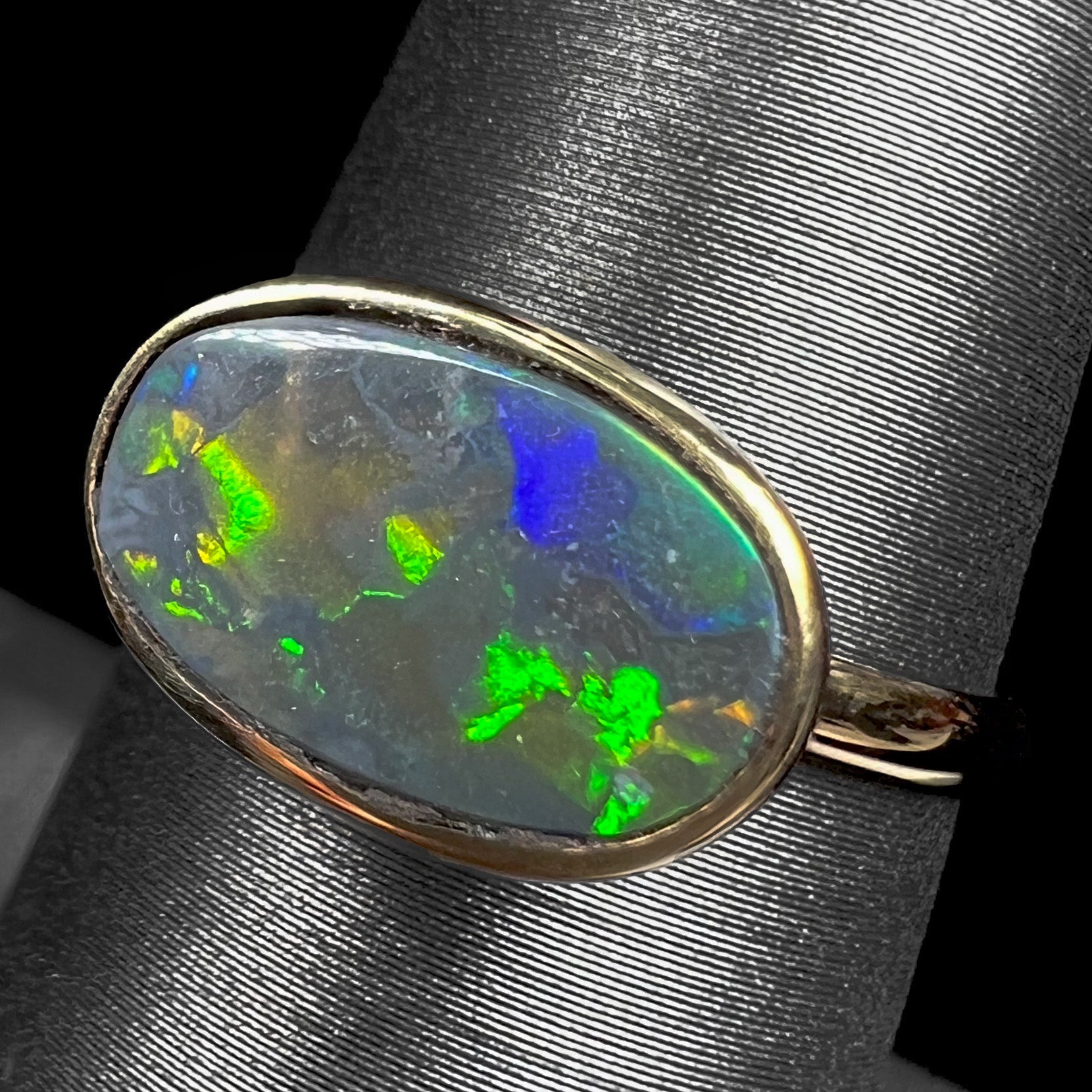 A ladies' yellow gold black opal solitaire ring from Lightning Ridge, Australia.
