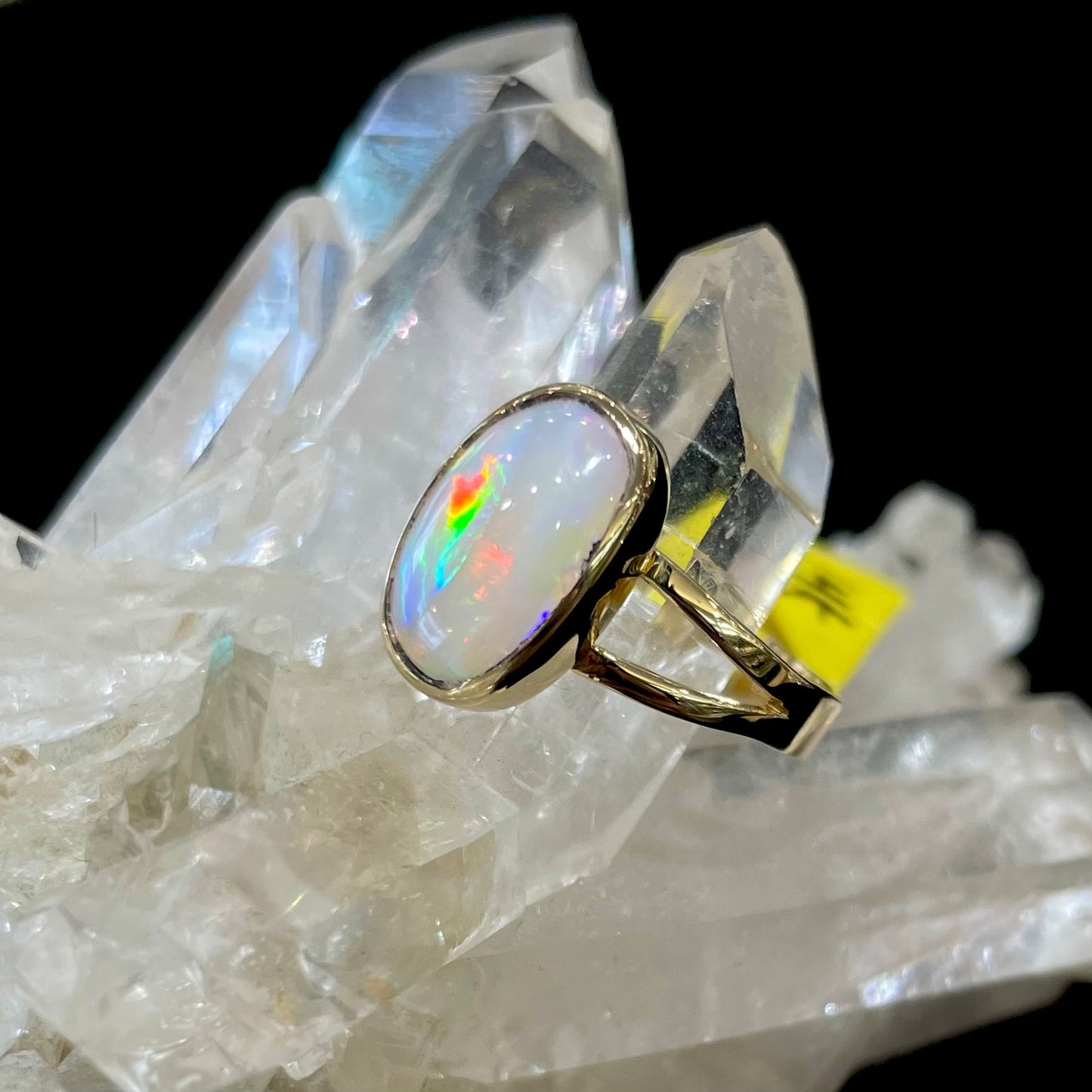 A handmade split shank white opal solitaire ring in yellow gold.
