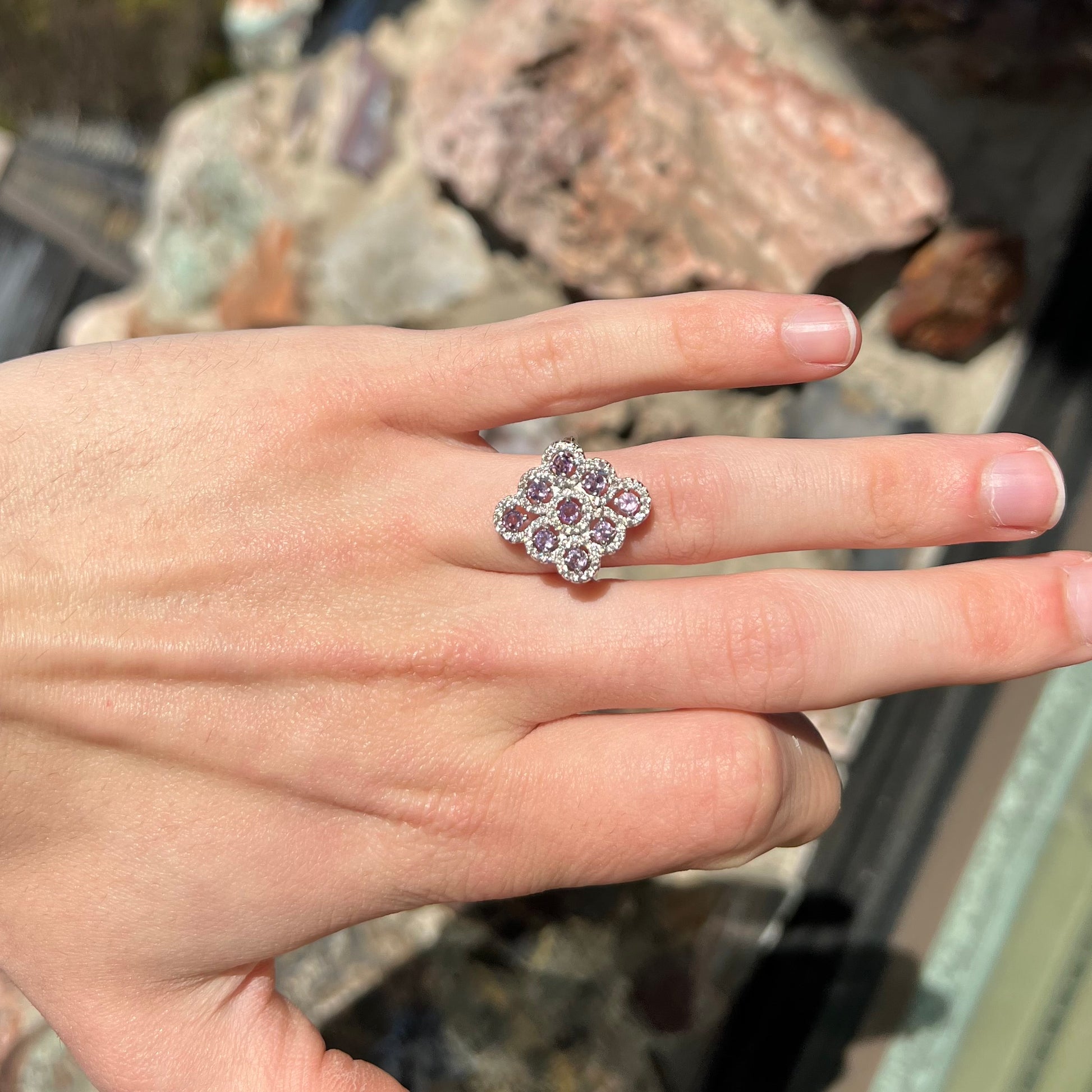 A silver ladies' ring set with 9 rose de France amethyst stones in white topaz halos.
