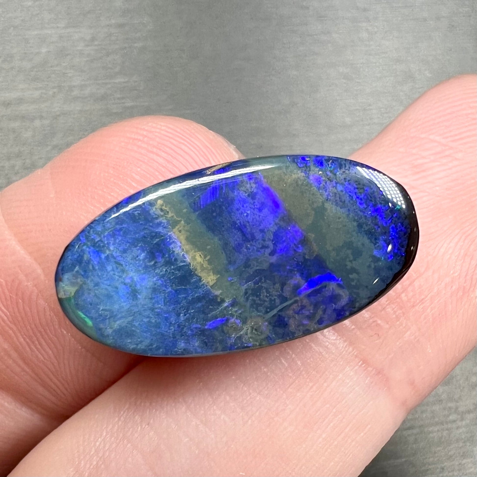 A loose, oval cabochon cut black boulder opal stone from Quilpie, Australia.