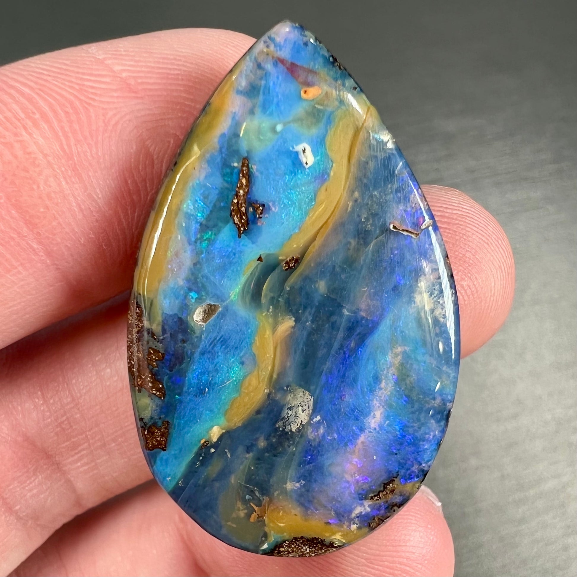 A loose, pear shaped cabochon cut boulder opal stone from Quilpie, Australia.