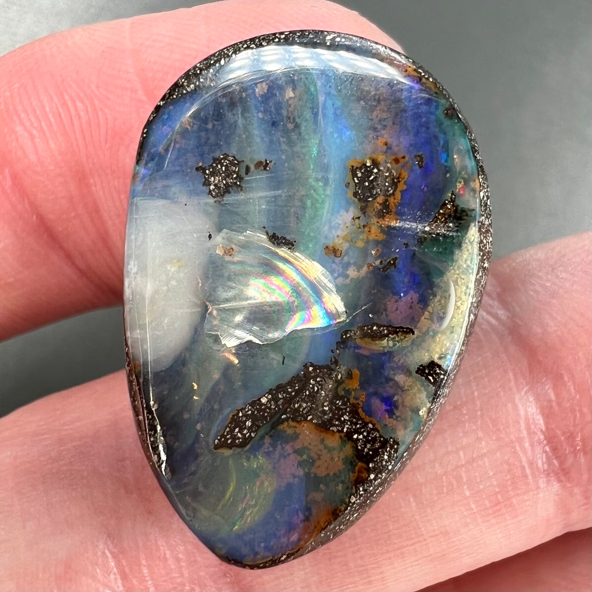 A loose, pear shaped Australian boulder opal.  The pattern on the opal resembles the face of a very sad man.