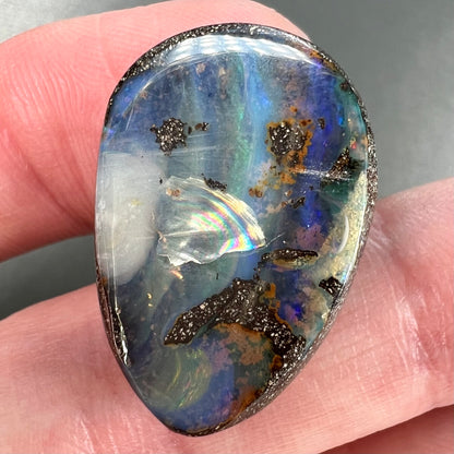 A loose, pear shaped Australian boulder opal.  The pattern on the opal resembles the face of a very sad man.