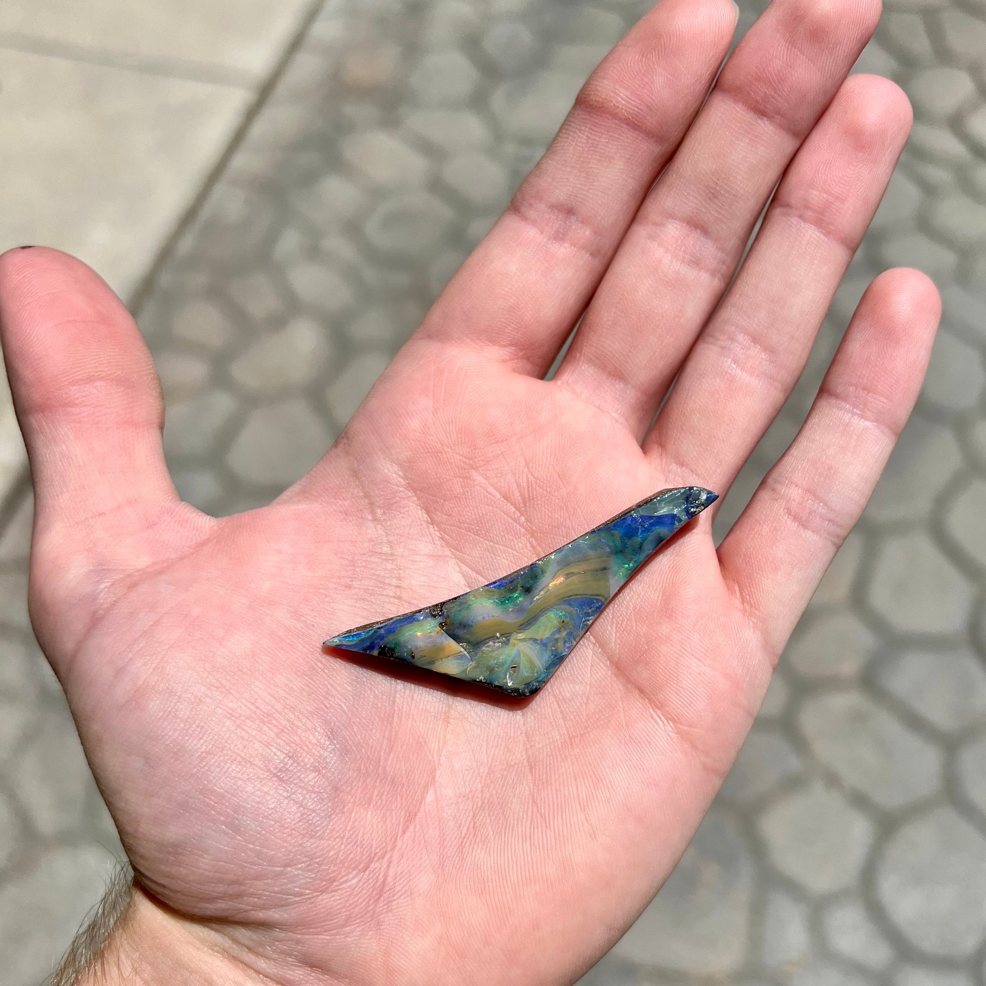 A loose, triangular shaped boulder opal stone from Queensland, Australia.