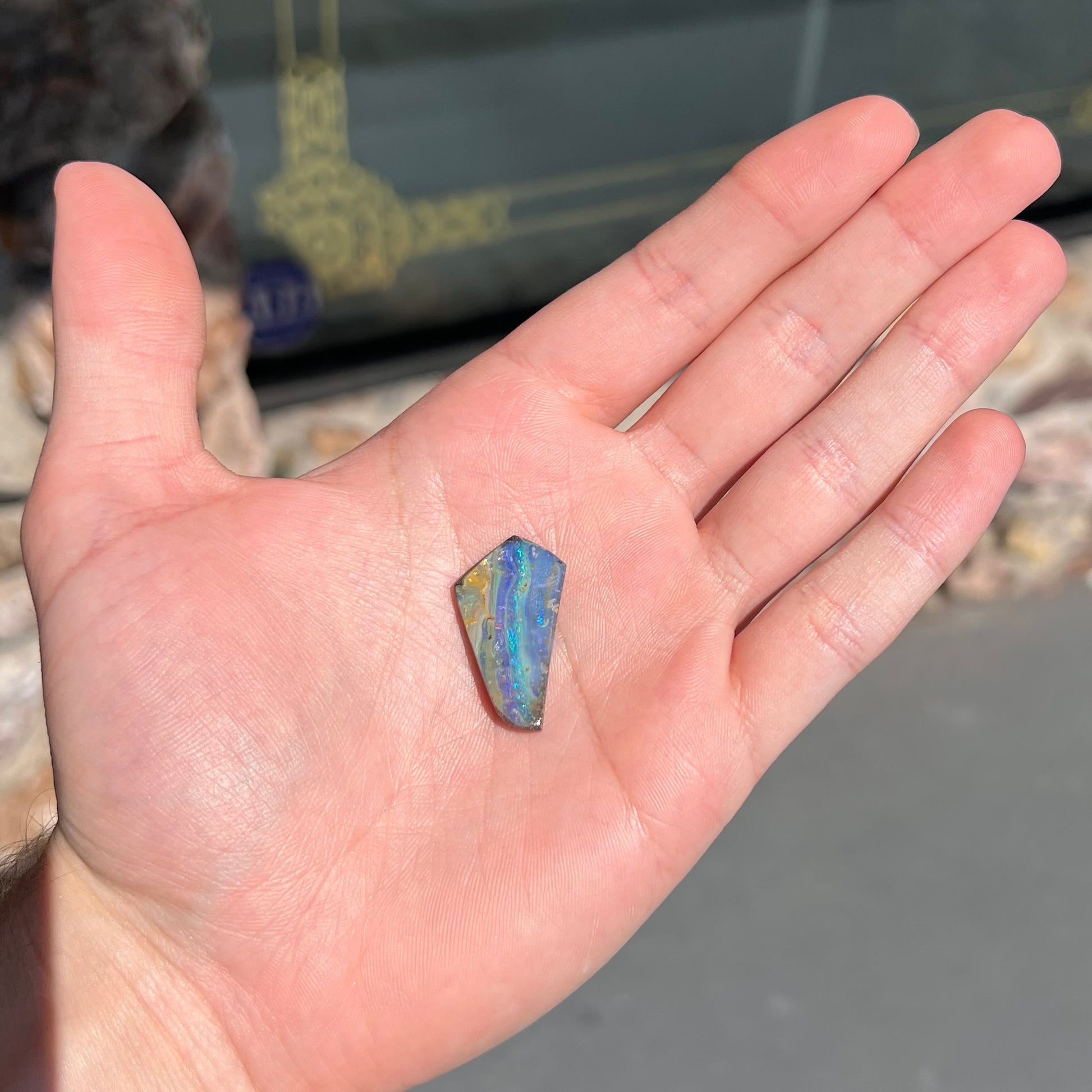 A loose, polished, freeform cut boulder opal stone from Queensland, Australia.