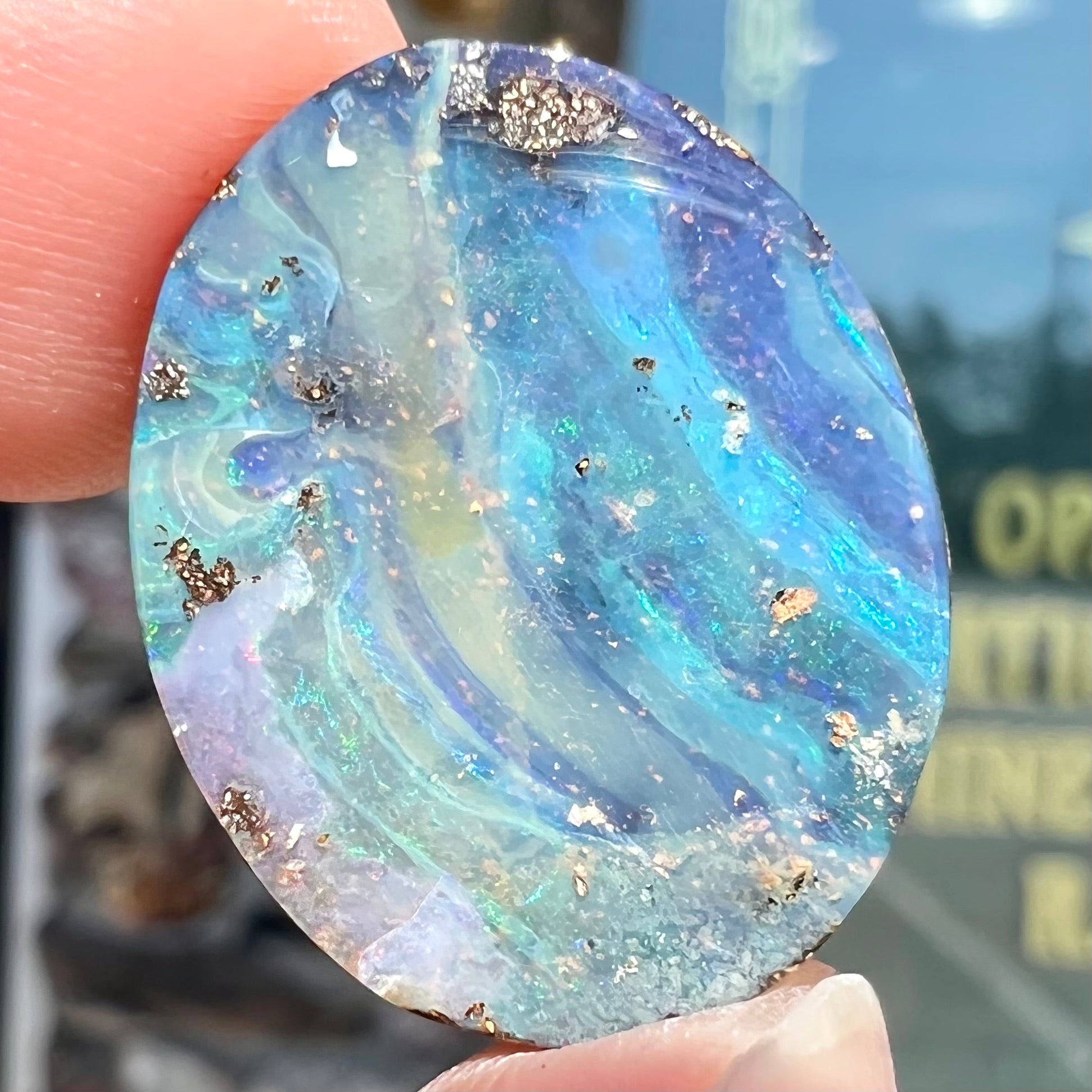 A loose, oval cabochon cut boulder opal stone from Queensland, Australia.  The stone is predominantly blue.