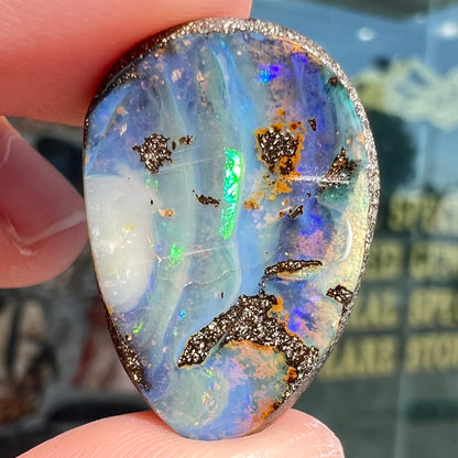 A loose, pear shaped Australian boulder opal.  The pattern on the opal resembles the face of a very sad man.