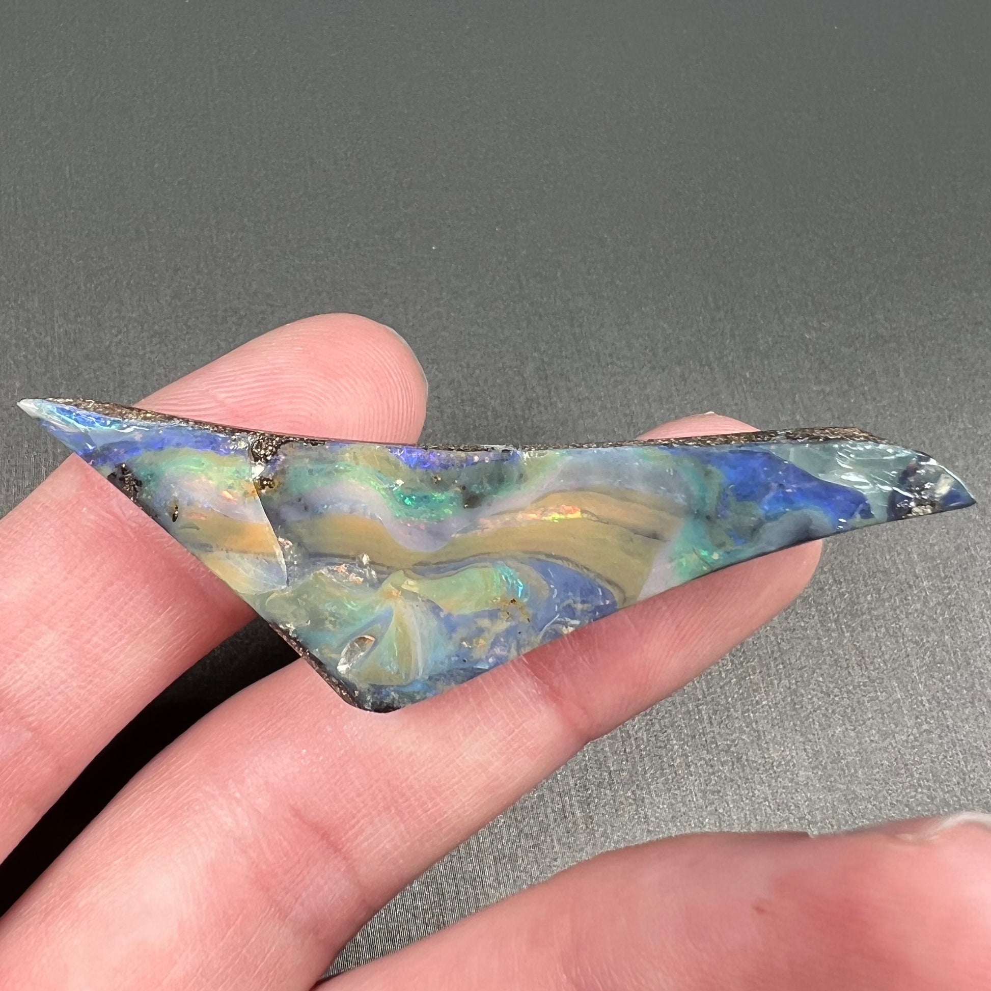 A loose, triangular shaped boulder opal stone from Queensland, Australia.