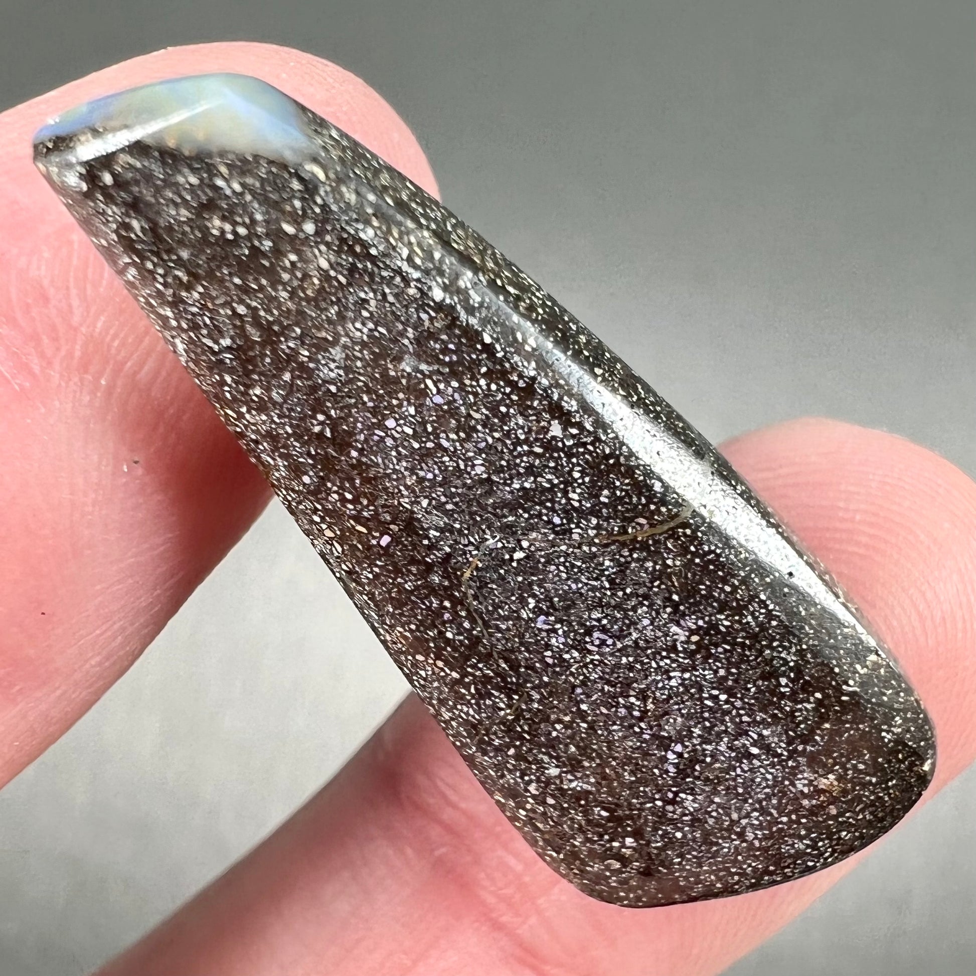 A loose, polished, freeform drop shaped boulder opal stone from Quilpie, Australia.