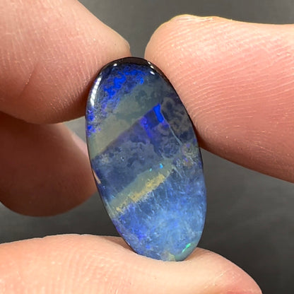 A loose, oval cabochon cut black boulder opal stone from Quilpie, Australia.