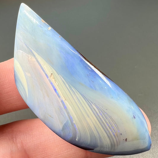 A loose, polished blue boulder opal stone from Queensland, Australia.