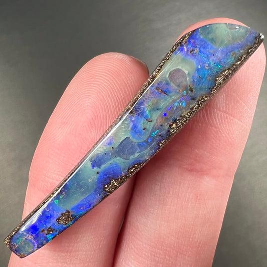 A loose, polished Quilpie boulder opal stone from Australia.  The stone is predominantly blue.