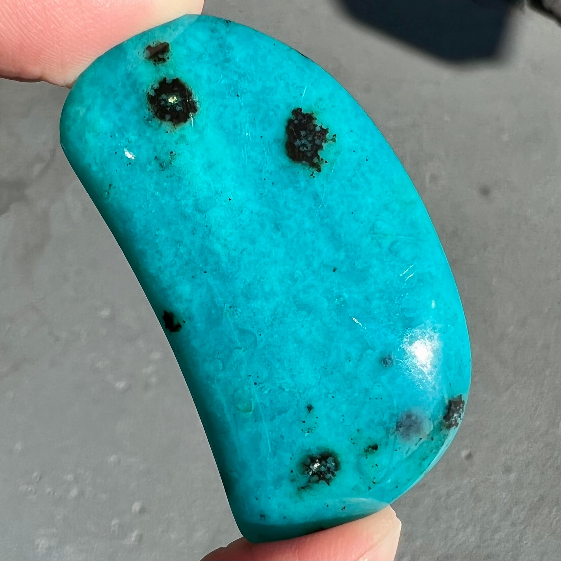 A loose, polished, spotted blue chrysocolla stone.