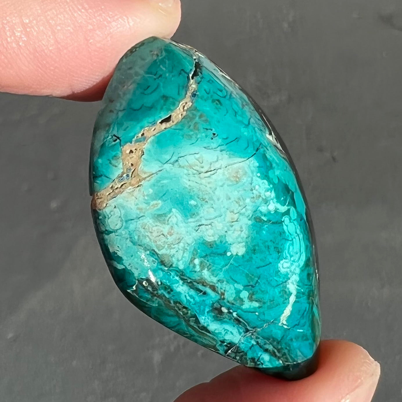 A loose chrysocolla stone with turquoise inclusions.