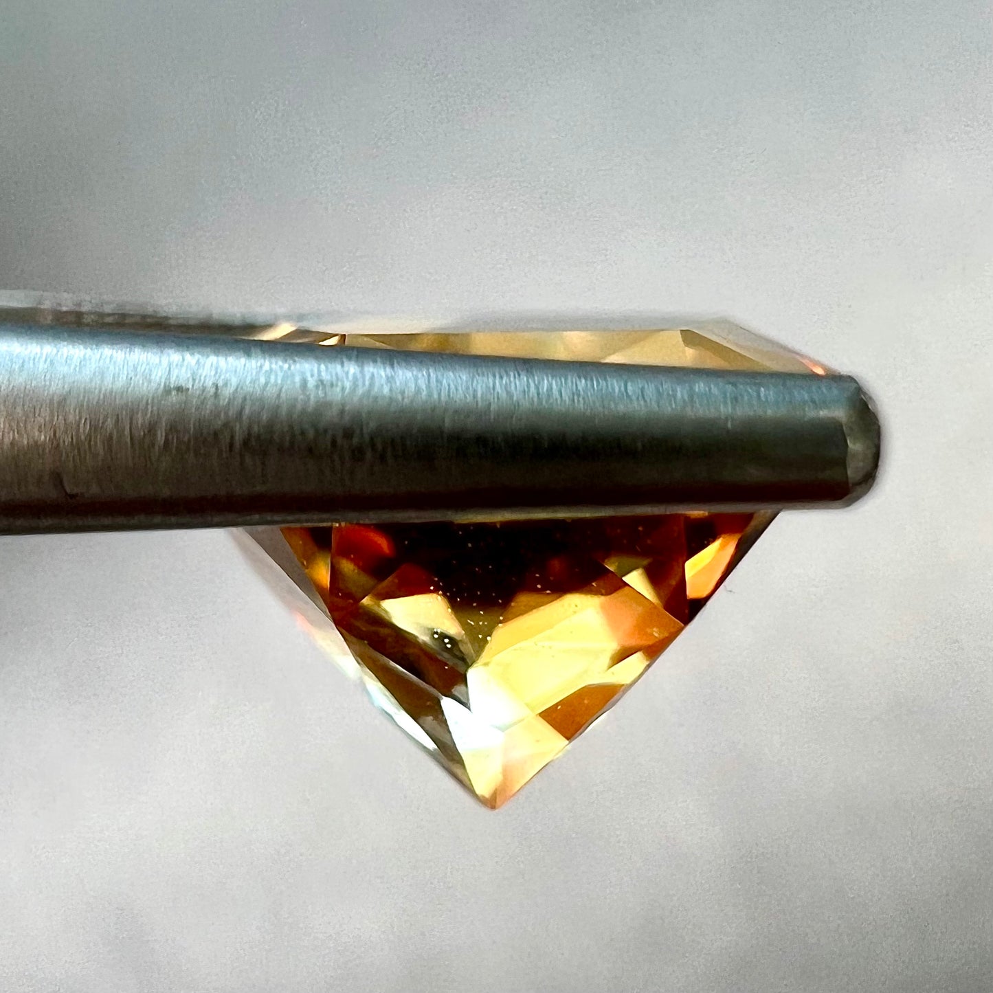 A loose, faceted round cut citrine stone with back facets that form a five pointed star.