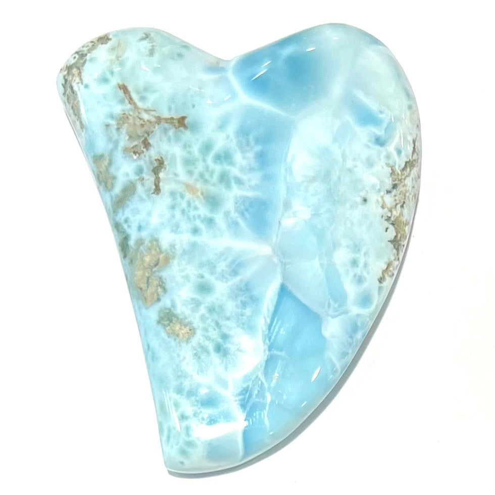 A loose larimar stone that has been hand-carved in the shape of a freeform heart.
