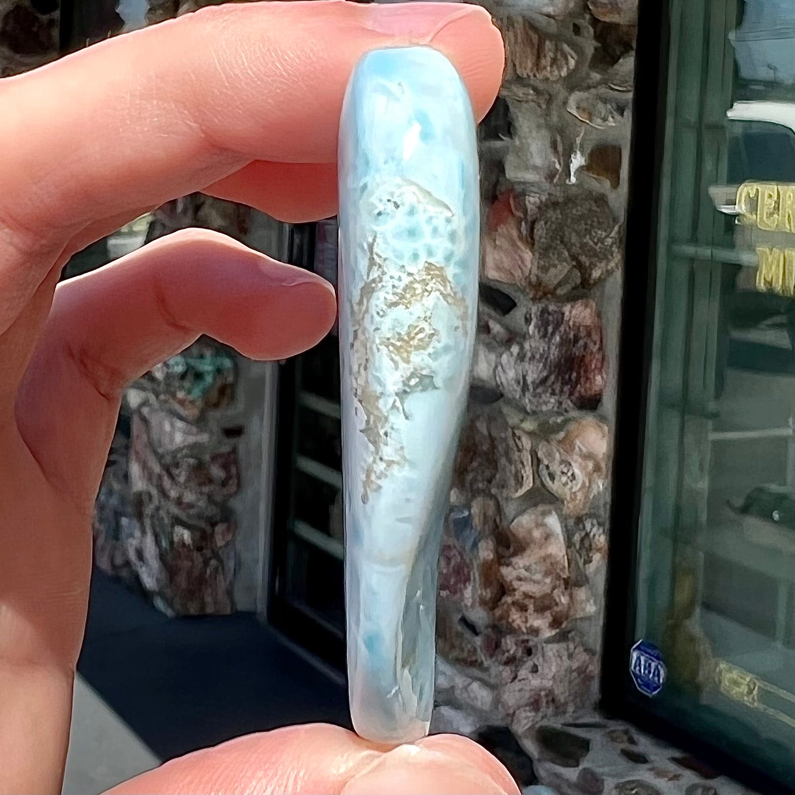 A loose larimar stone that has been hand-carved in the shape of a freeform heart.