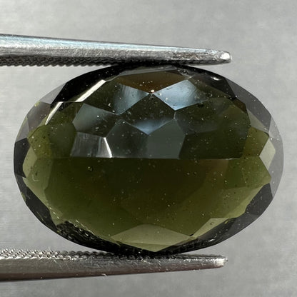 A loose faceted oval checkerboard cut moldavite stone.
