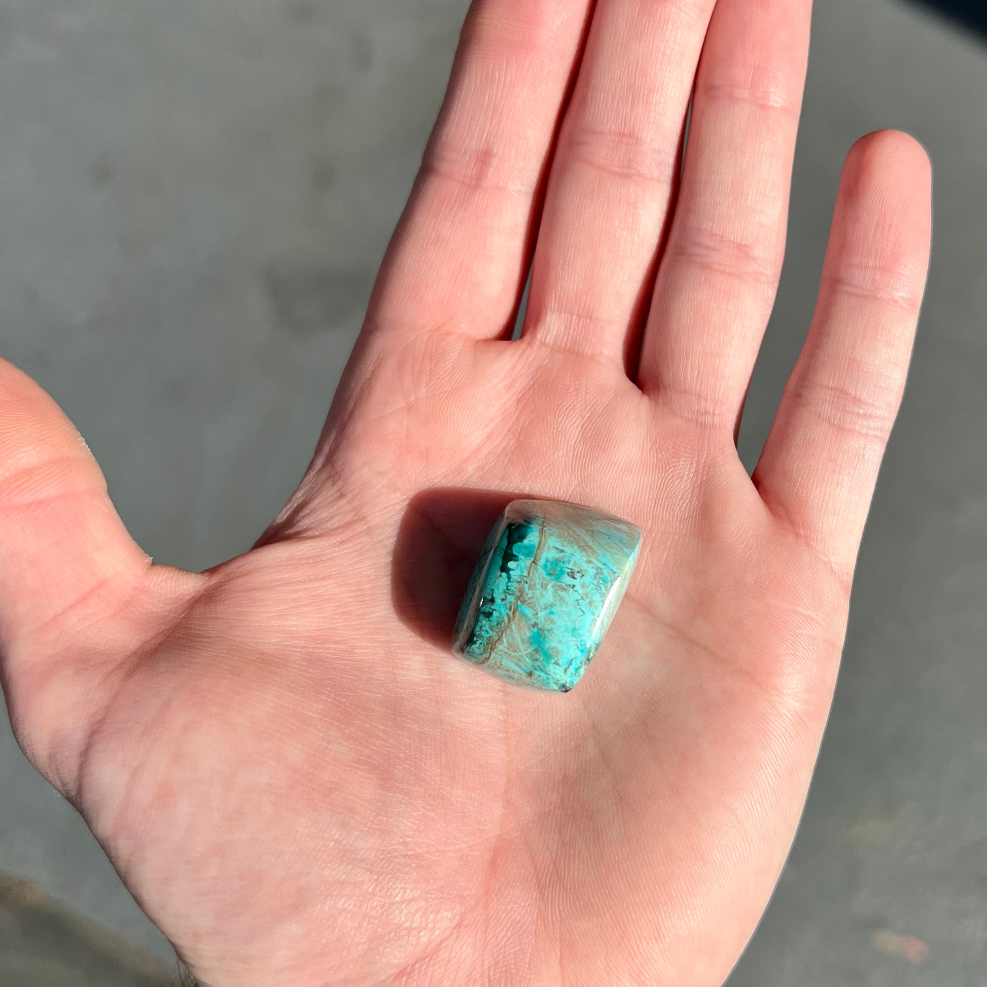 A loose, polished turquoise specimen with azurite inclusions.
