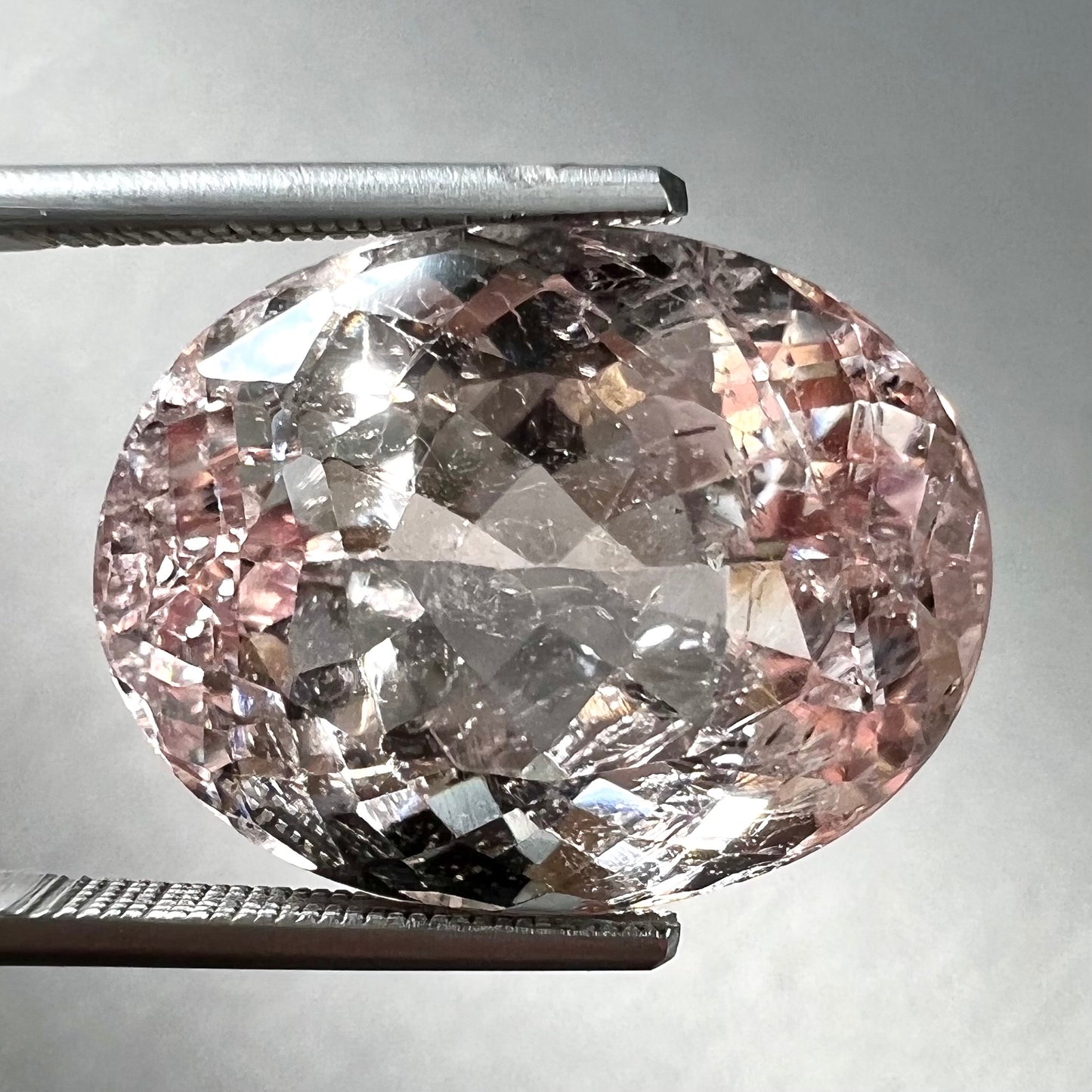 A loose, faceted oval cut pink morganite stone weighing over 14 carats.