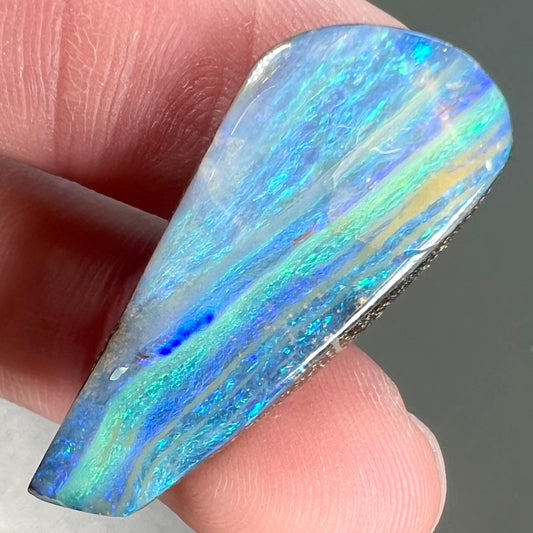 A loose, polished, freeform drop shaped boulder opal stone from Quilpie, Australia.