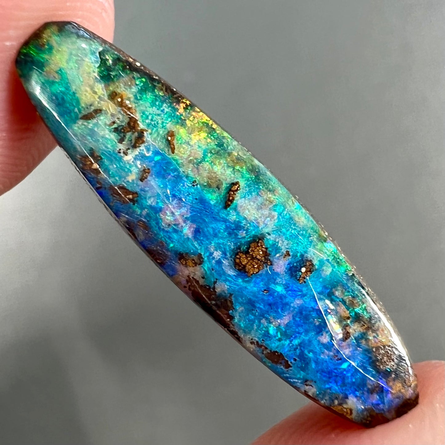 A loose, oval cabochon cut Australian boulder opal from Quilpie, Australia.  Predominant colors are blue and green.