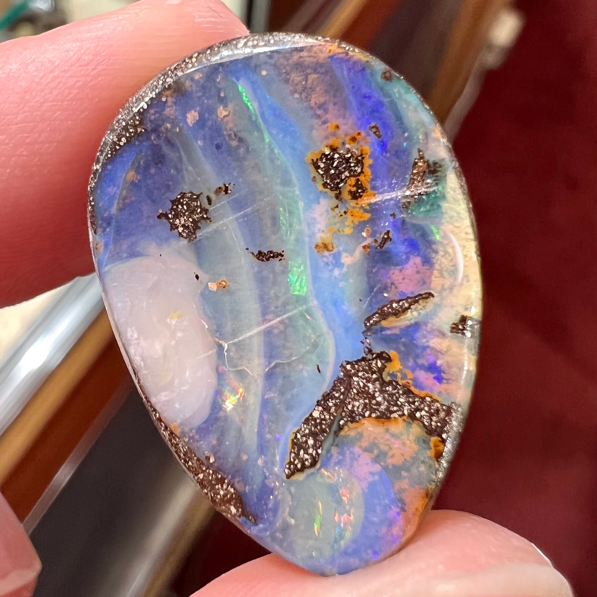 A loose, pear shaped Australian boulder opal.  The pattern on the opal resembles the face of a very sad man.