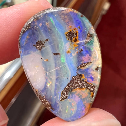 A loose, pear shaped Australian boulder opal.  The pattern on the opal resembles the face of a very sad man.
