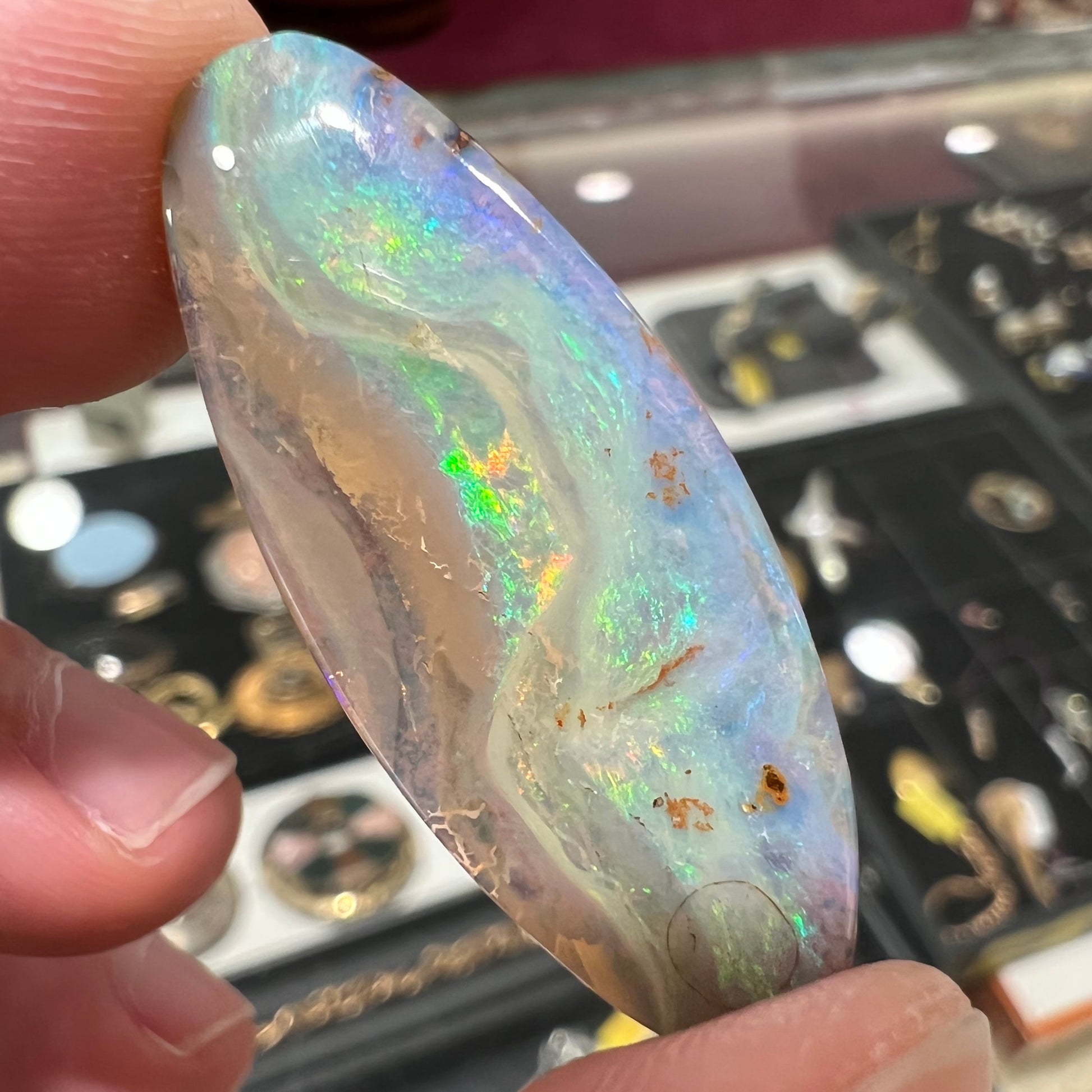 A loose, oval cabochon cut opal from Quilpie, Australia.  Blue, red, and green colors can be seen.