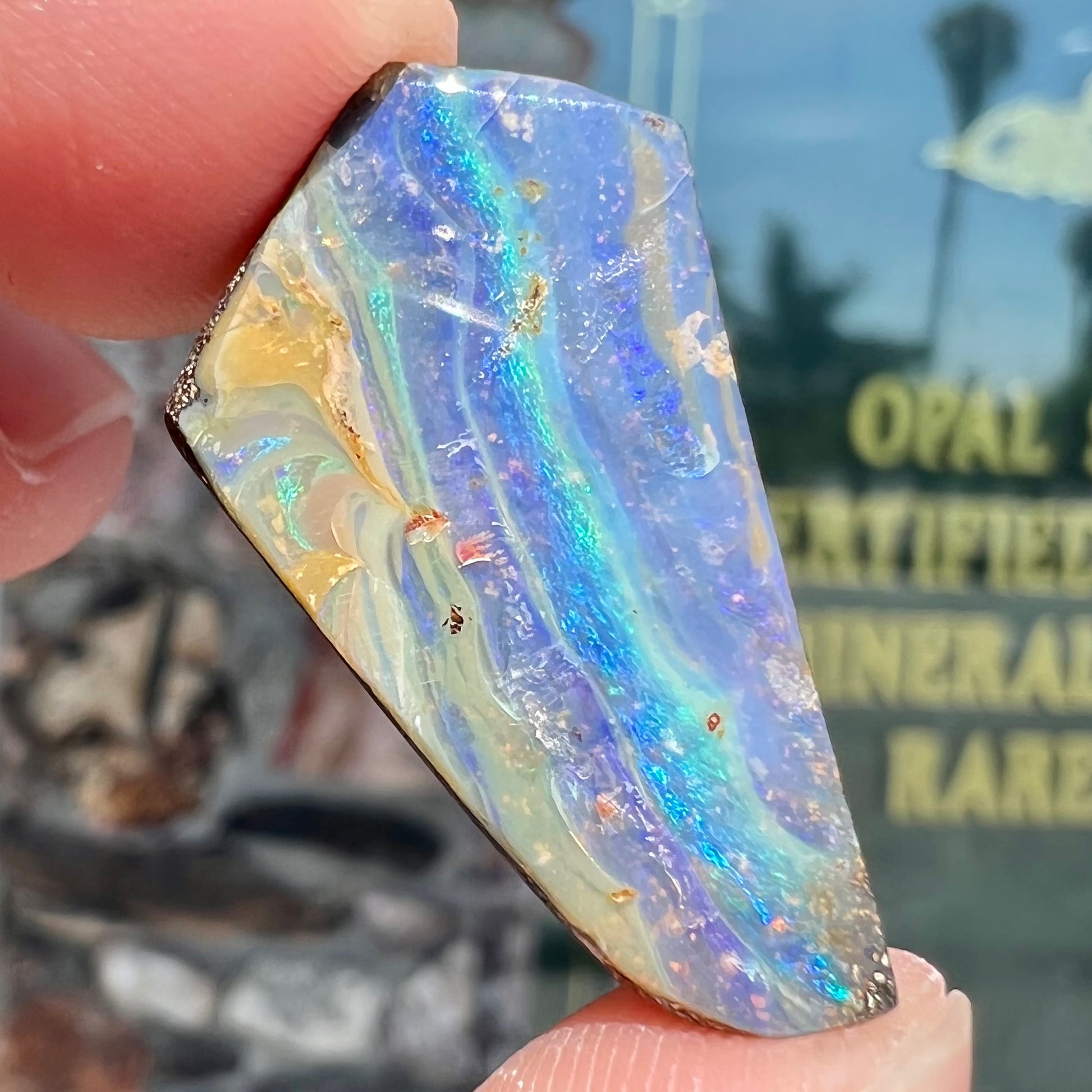 A loose, polished, freeform cut boulder opal stone from Queensland, Australia.