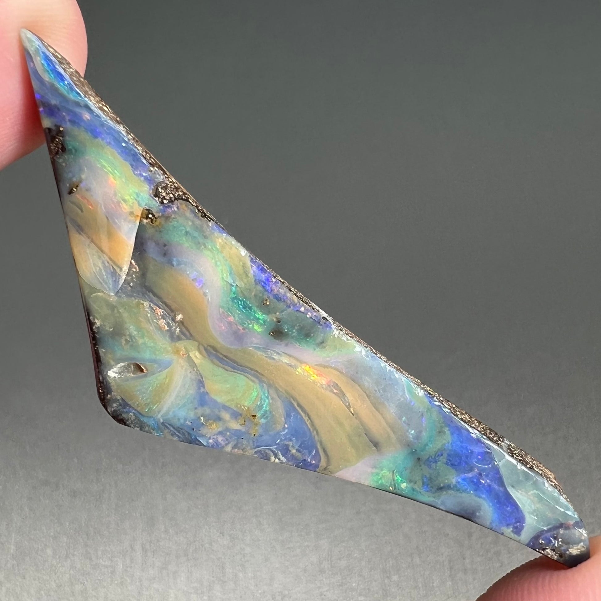 A loose, triangular shaped boulder opal stone from Queensland, Australia.