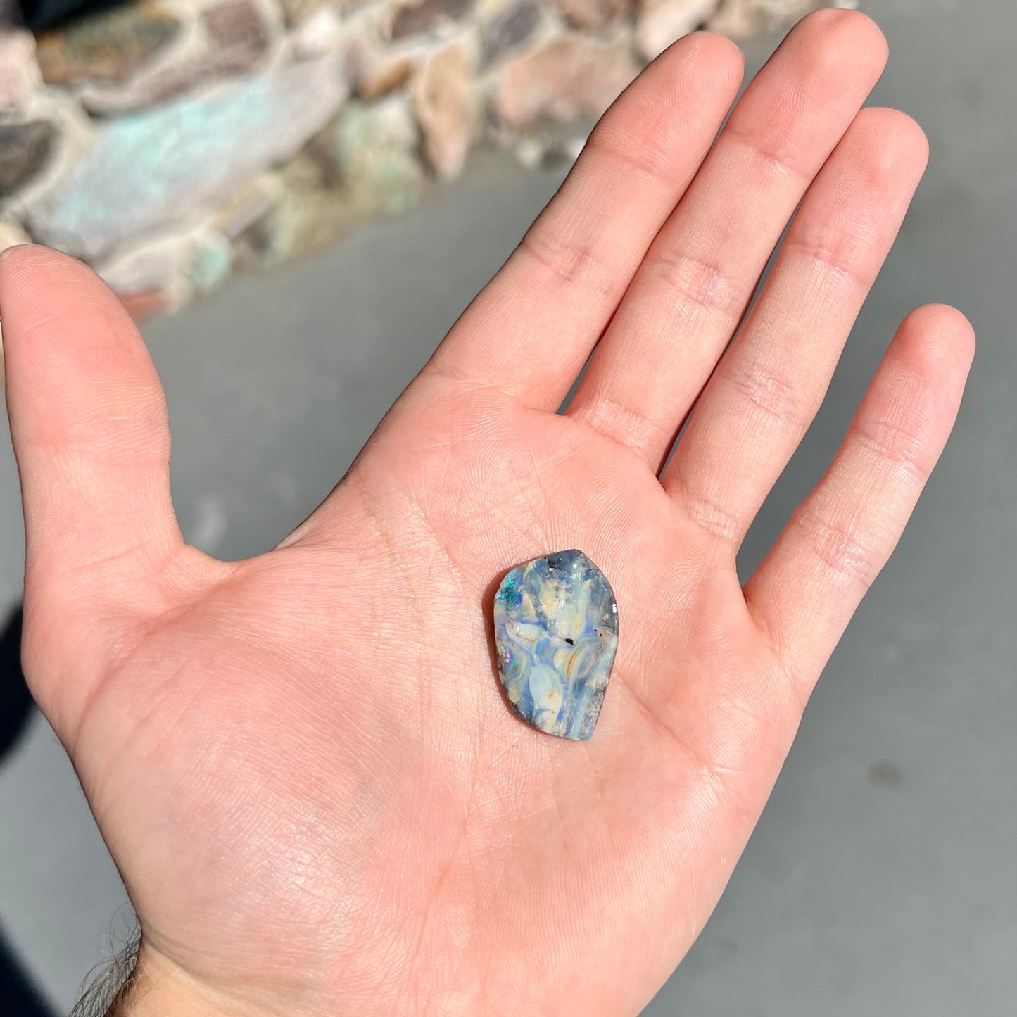 A loose, polished, freeform cut boulder opal stone from Queensland, Australia.