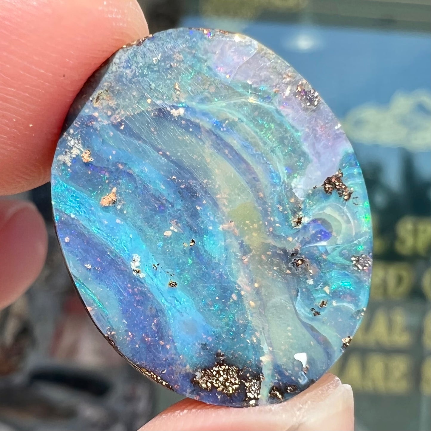 A loose, oval cabochon cut boulder opal stone from Queensland, Australia.  The stone is predominantly blue.