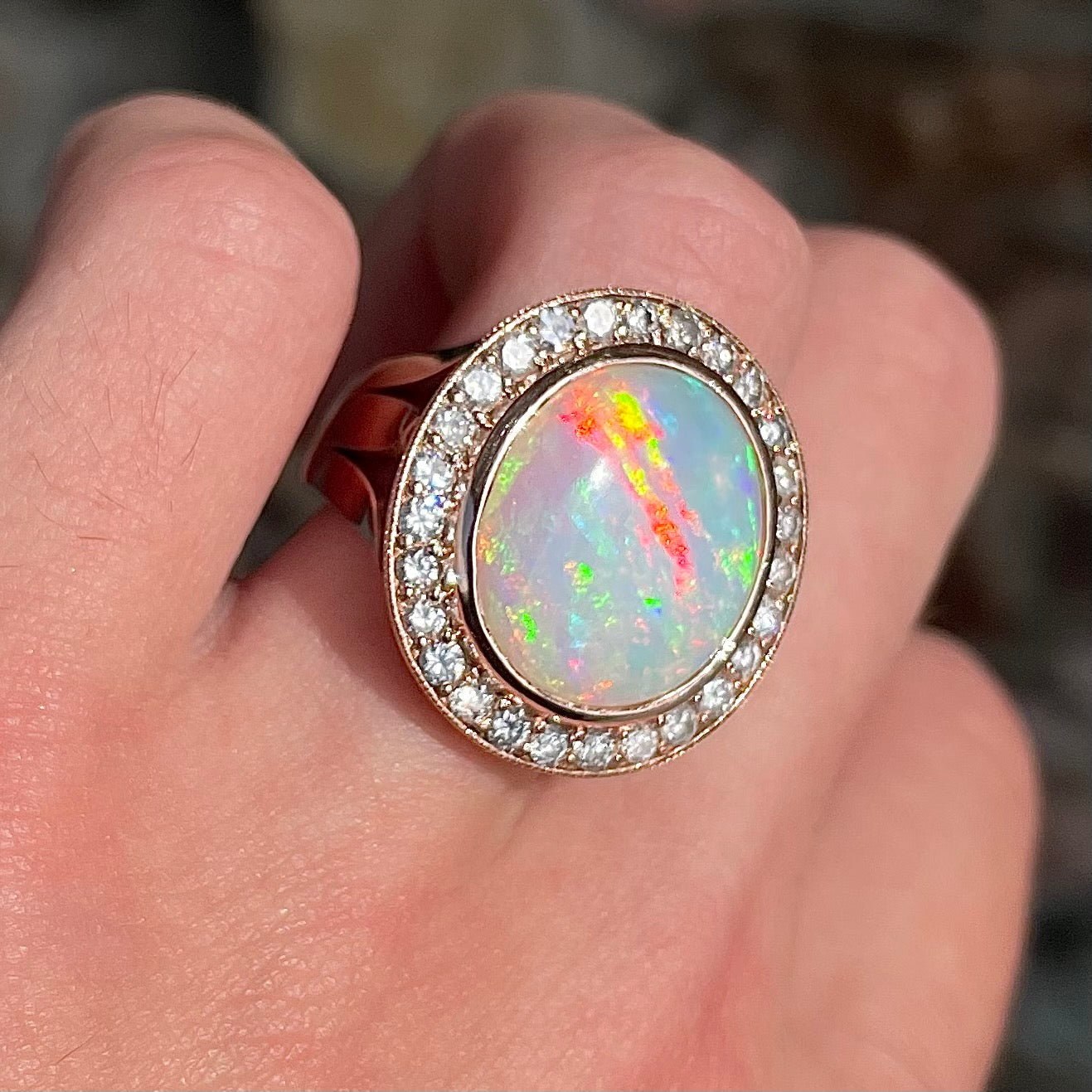 A large, Australian white crystal opal set in a rose gold and diamond halo ring.