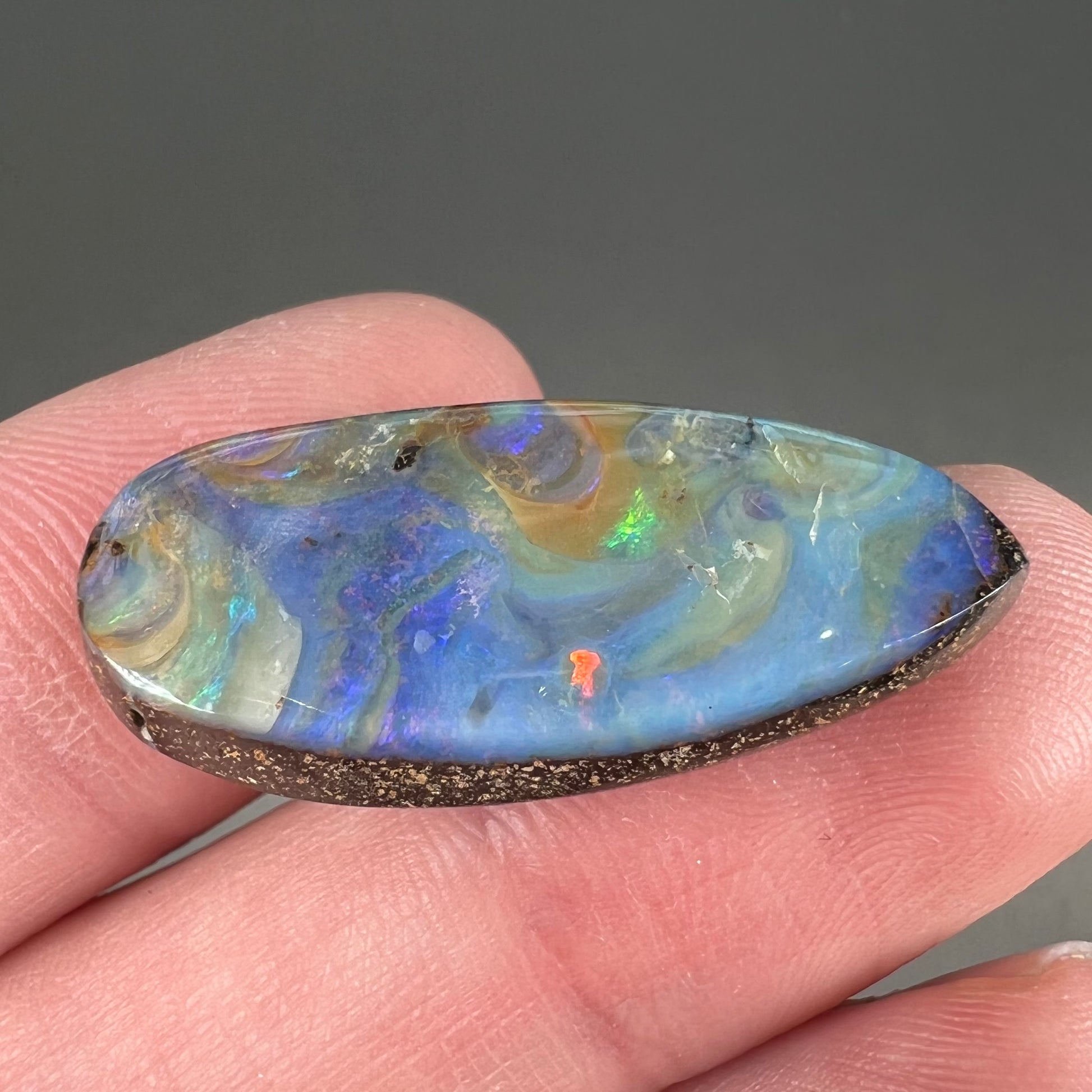 A loose, natural, pear shaped boulder opal stone from Quilpie, Australia.