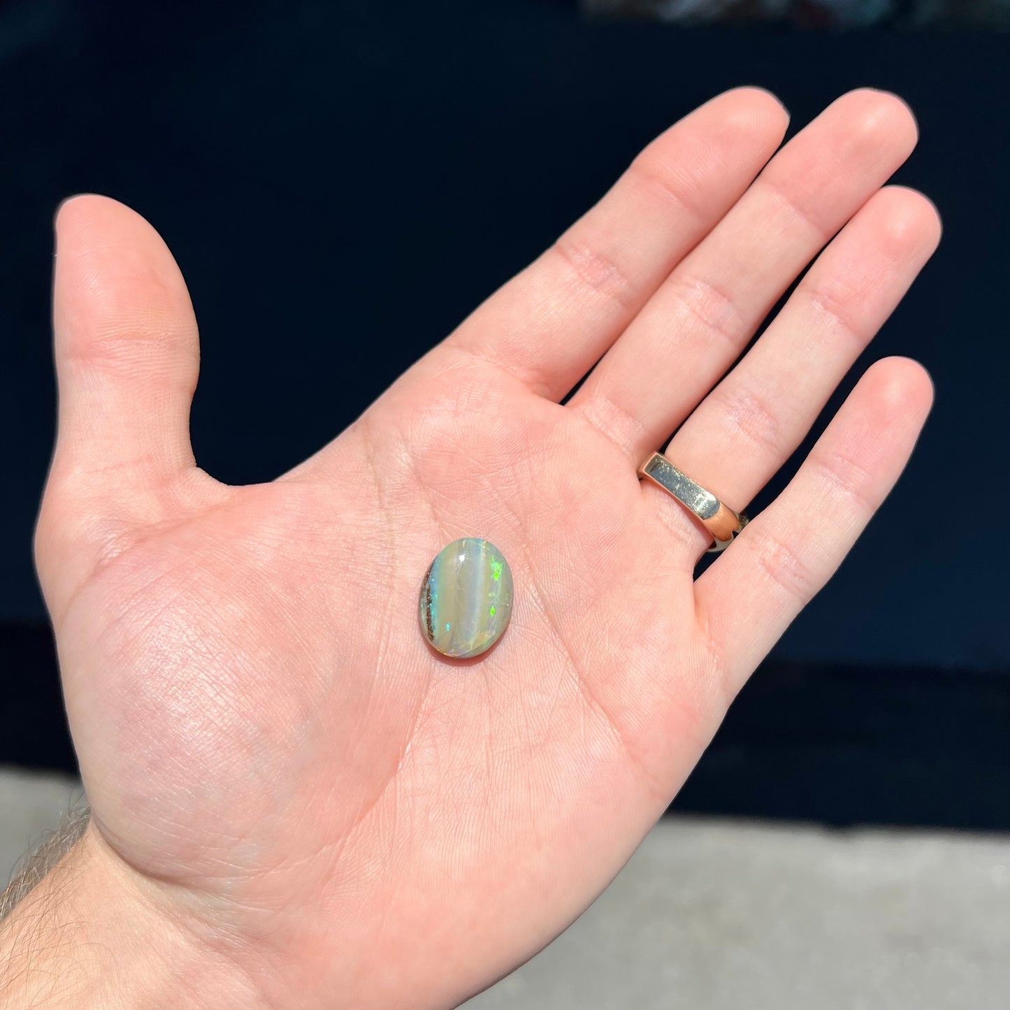 A loose, oval cabochon cut Quilpie boulder opal stone from Queensland, Australia.  The predominant color flash is green.