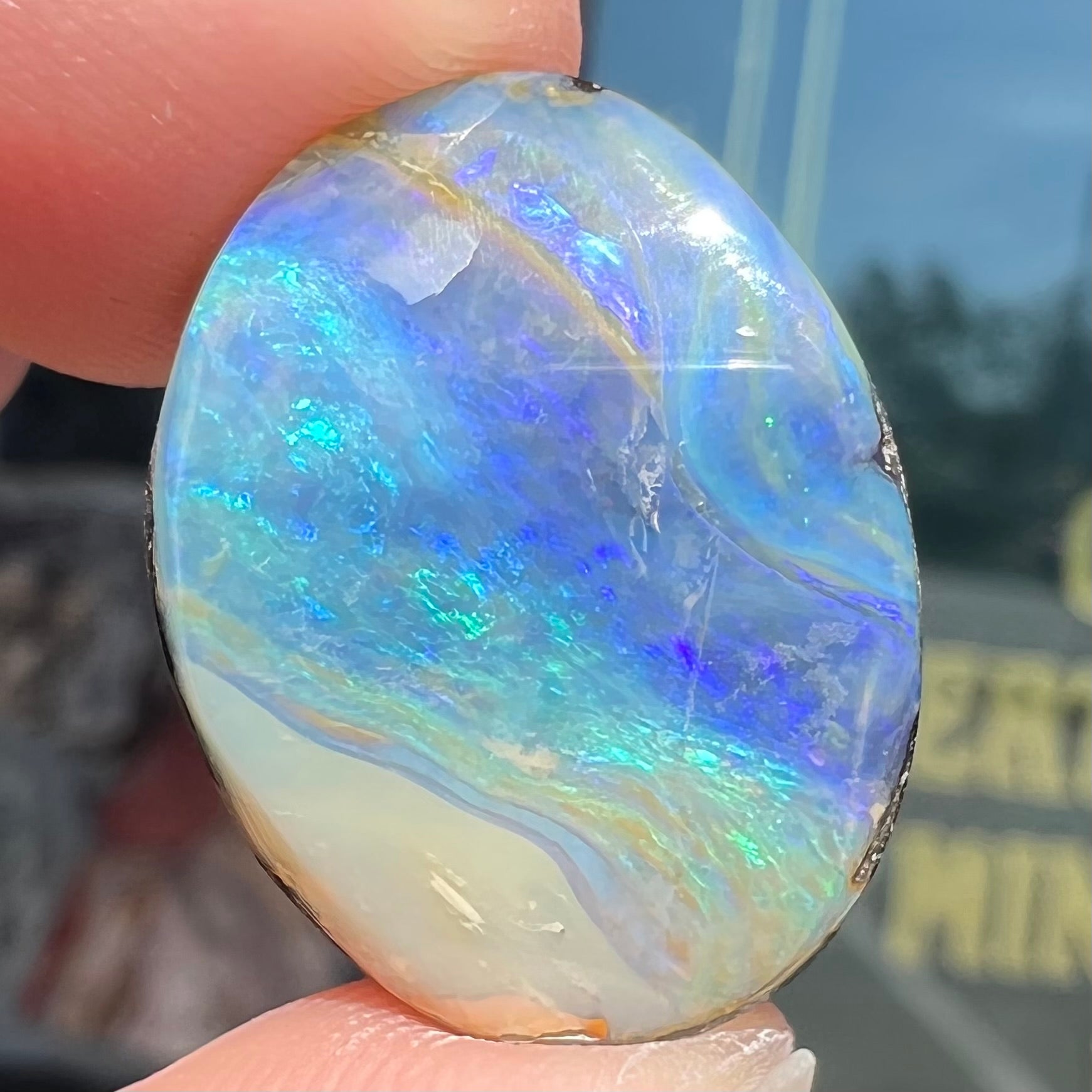 A loose, oval cabochon cut Australian boulder opal stone.