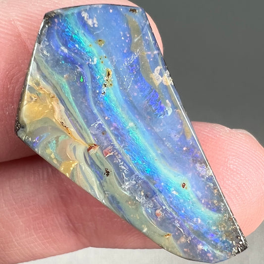 A loose, polished, freeform cut boulder opal stone from Queensland, Australia.