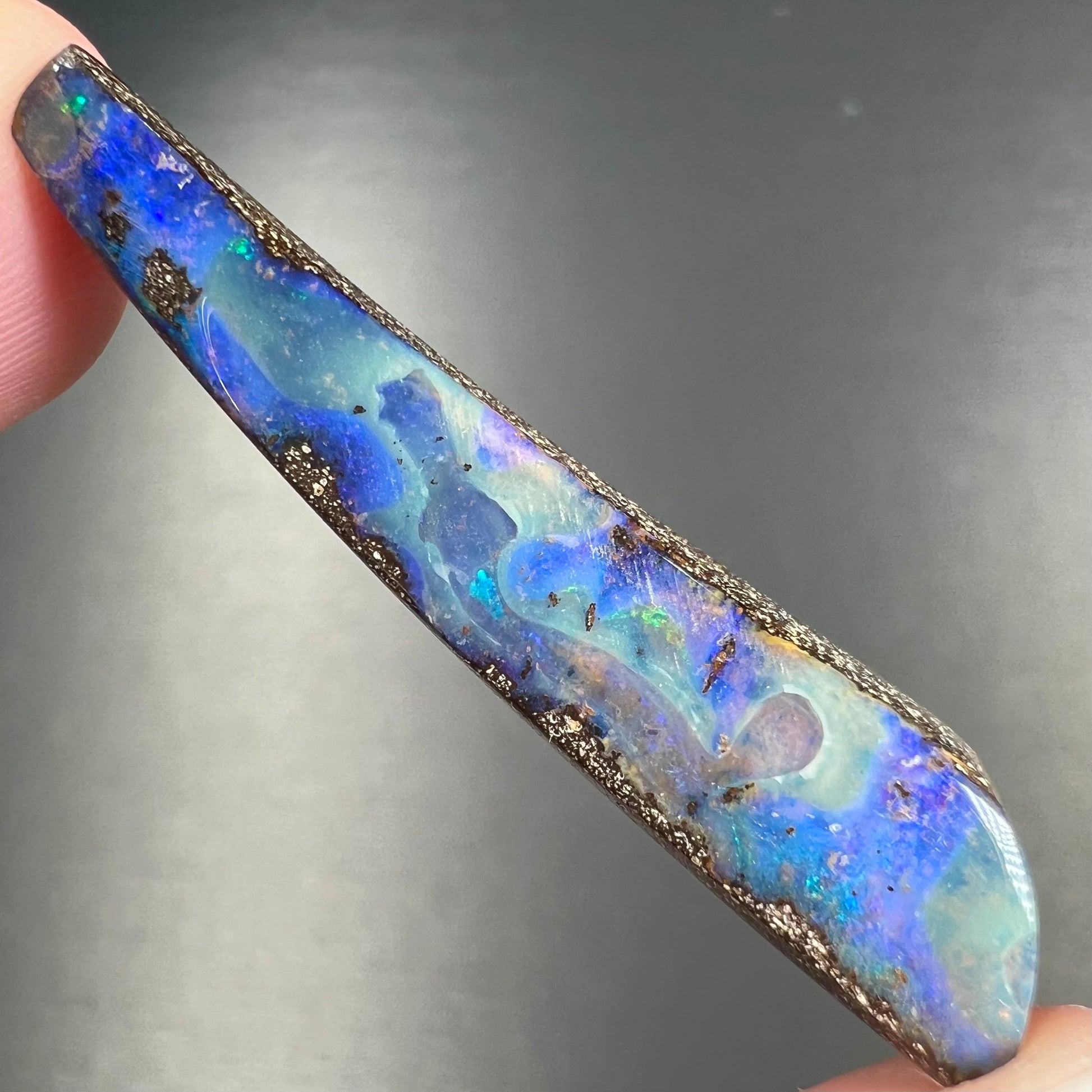 A loose, polished Quilpie boulder opal stone from Australia.  The stone is predominantly blue.