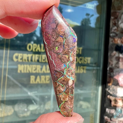 A loose, freeform cabochon cut Koroit boulder opal stone.
