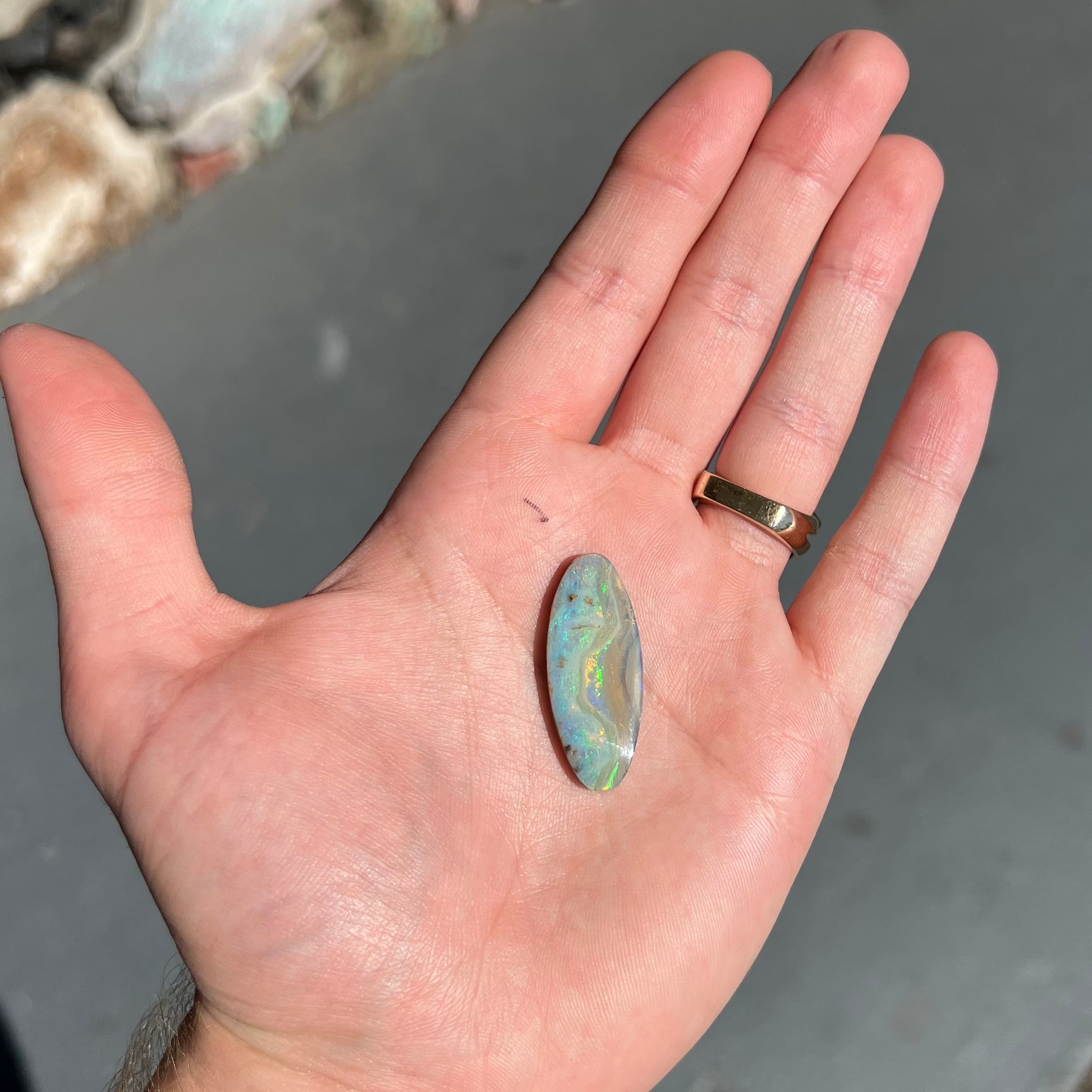 A loose, oval cabochon cut opal from Quilpie, Australia.  Blue, red, and green colors can be seen.