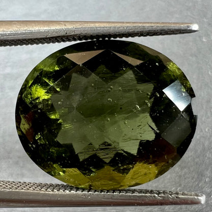 A faceted oval checkerboard cut moldavite gemstone that weighs 4.14 carats.