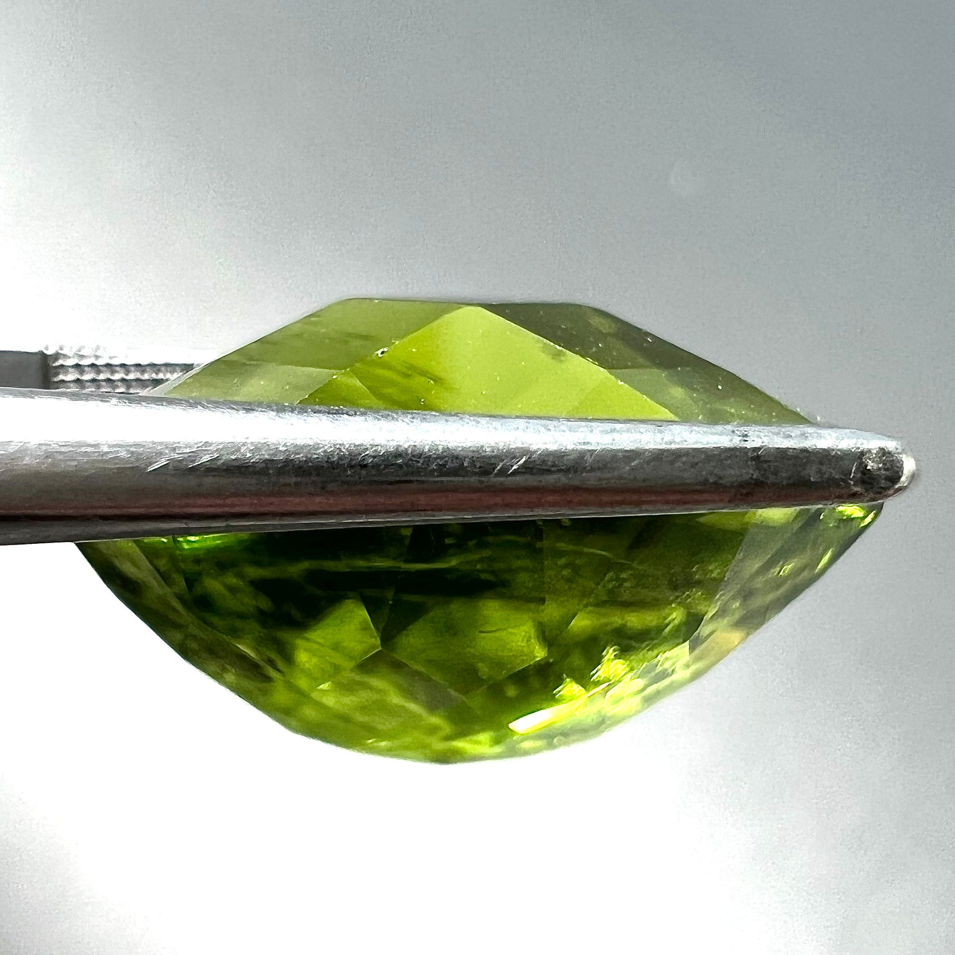 A loose, faceted oval checkerboard cut peridot gemstone from Pakistan.